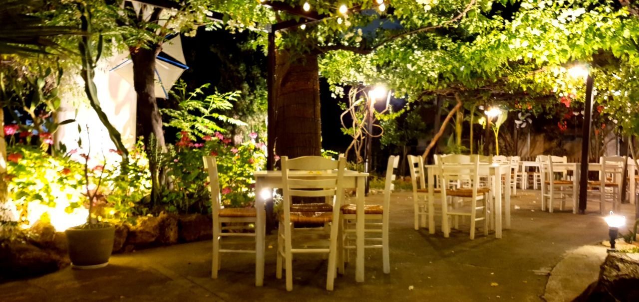 Garden tables glowing under warm lamps in the evening